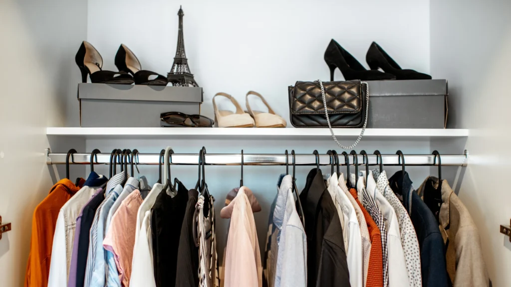 A well-organized walk-in closet filled with a variety of clothing and shoes, including dresses, pants, tops, and high heels.